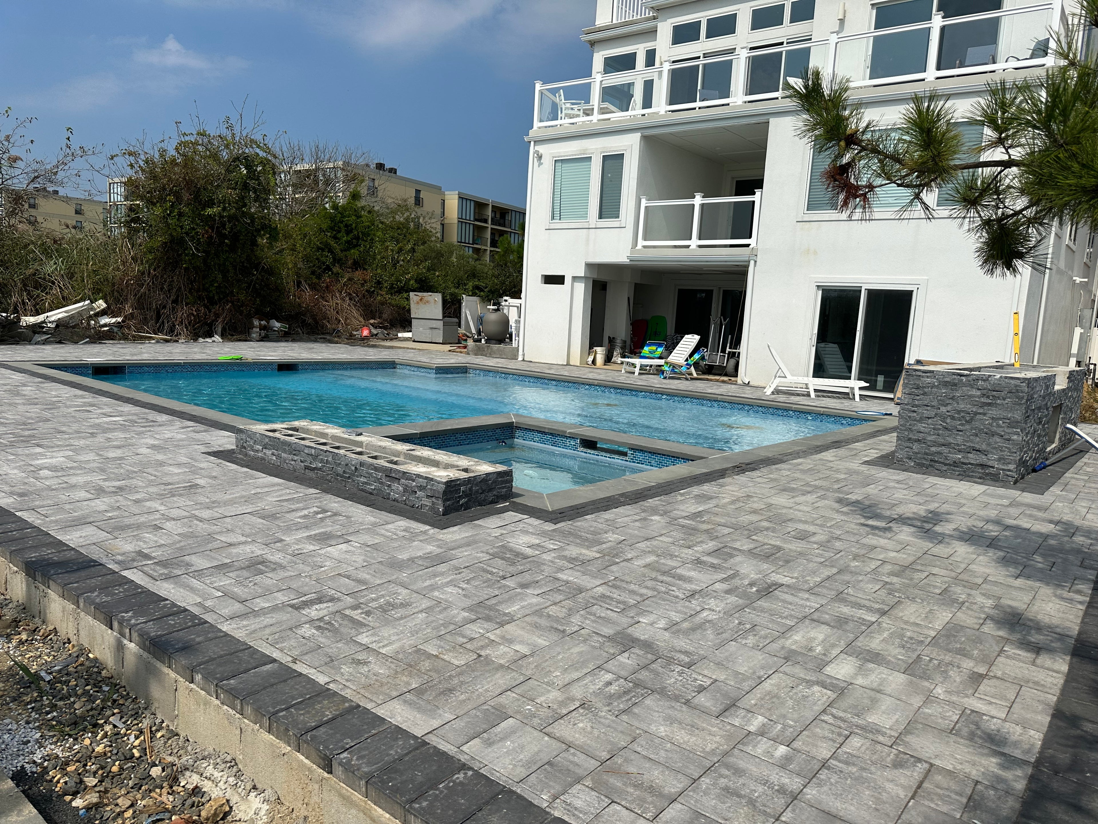 Modern house with a pool area featuring paver work and surrounding greenery.