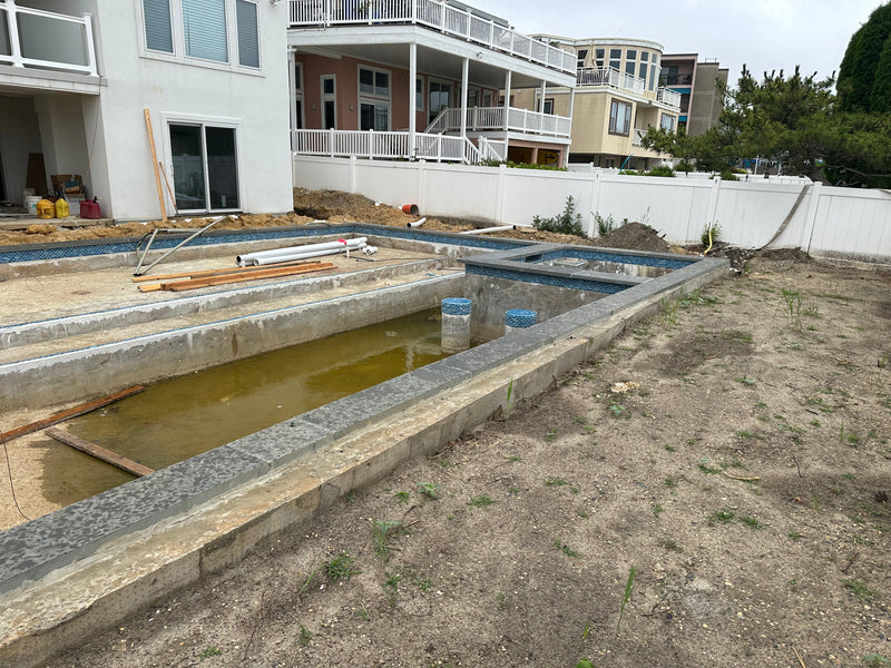 Construction site of a pool with surrounding houses in the background